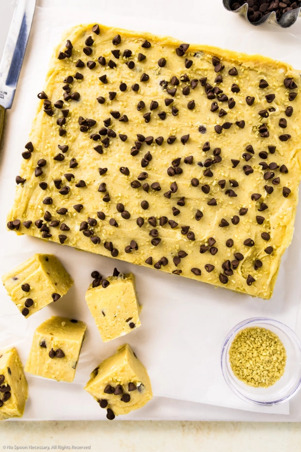 Overhead photo of a block of Pumpkin Fudge on a white cutting board with a few pieces of fudge cut into individual square servings. 