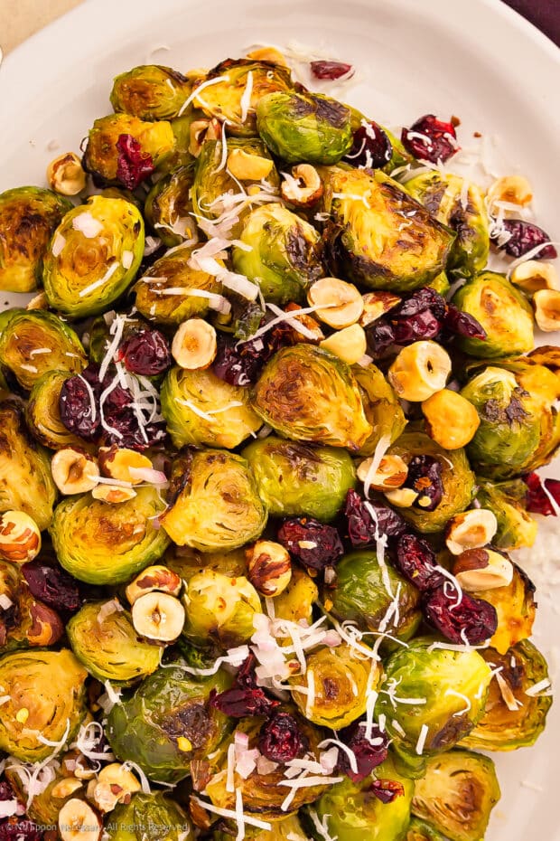 Overhead photo of roasted brussels sprouts with maple on a white serving platter.