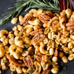 Overhead, landscape photo of Savory & Spicy Rosemary Roasted Nuts spilling out of a red martini glass with fresh rosemary.