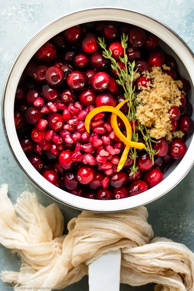 Overhead photo of white saucepan filled with all the ingredients needed to prepare cranberry relish.