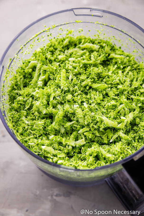 Overhead angled shot of a food processor bowl filled with broccoli "rice".