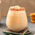 Straight on photo of two sugar cookie martinis garnished with a sprinkle rim and whipped cream.