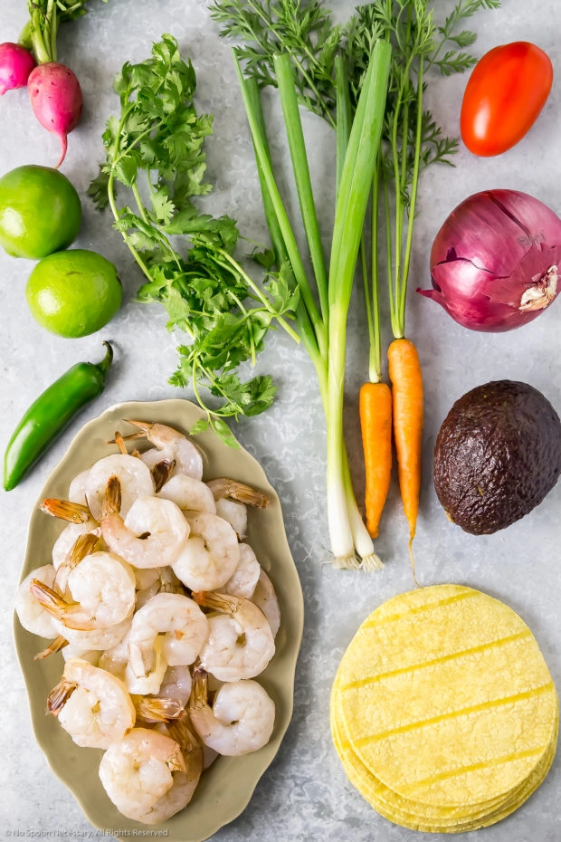 Overhead photo of all the ingredients needed to make Mexican ceviche neatly arranged on a gray surface.