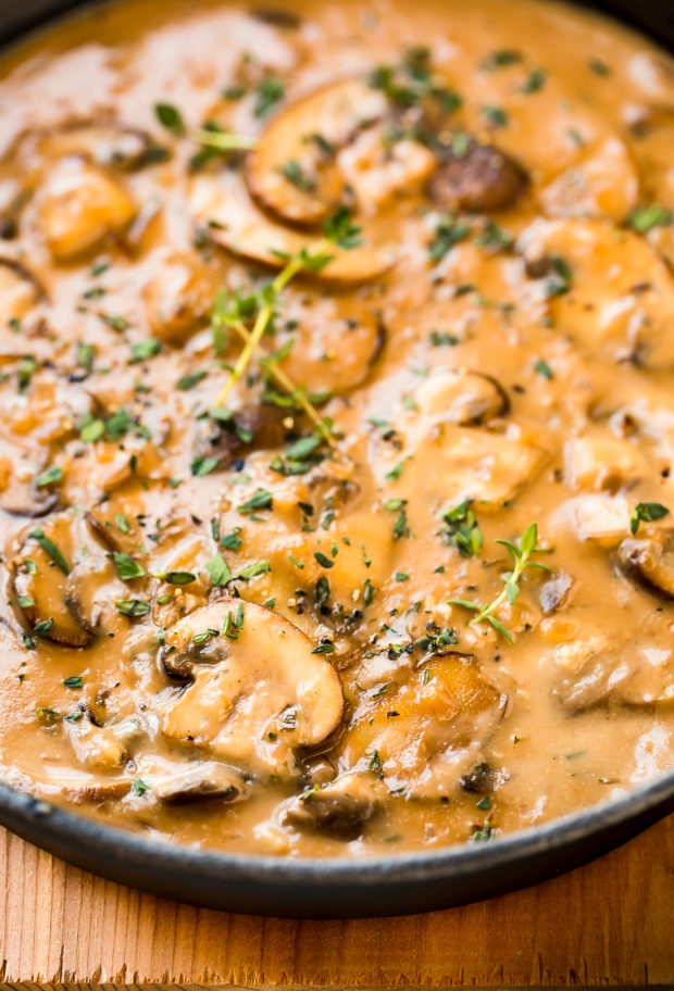 Angled, close-up photo Easy Mushroom Sauce garnished with fresh herbs in a small black cast iron skillet.