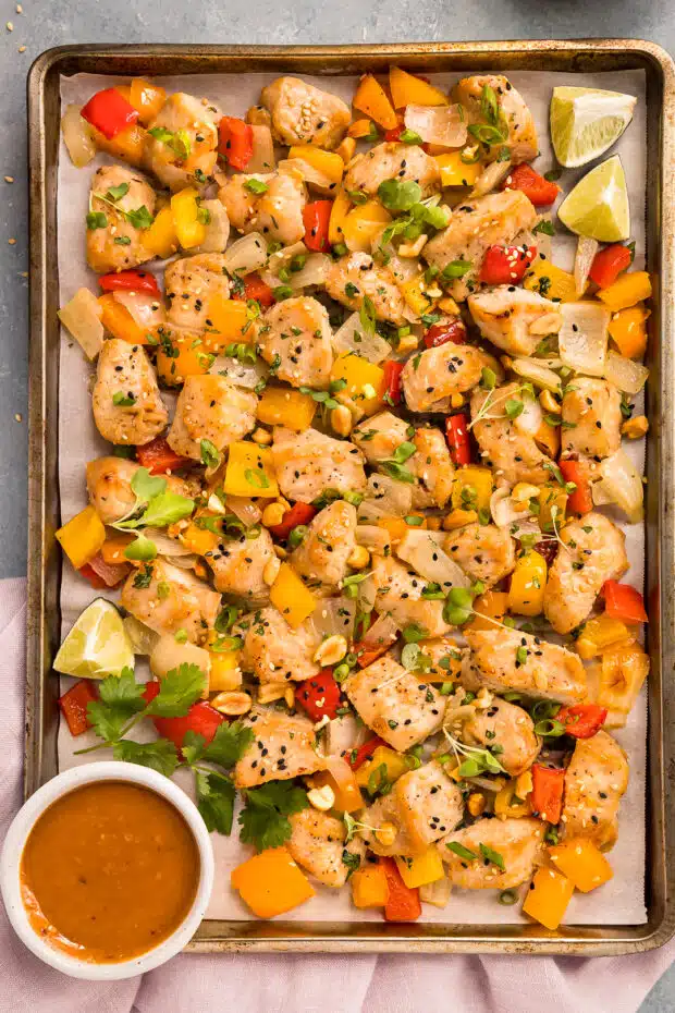 Overhead photo of Thai peanut chicken with vegetables on a baking sheet.