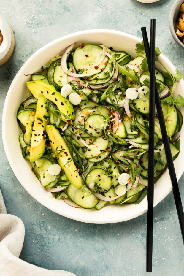 Overhead photo of cold Cucumber Salad in a white bowl with black chopsticks resting on the side of the bowl. 