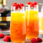 Straight on photo of two champagne cocktails made with fresh fruit puree and blood orange liqueur in a tall champagne flutes.
