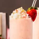 Straight on photo of two milkshakes with alcohol and strawberries.
