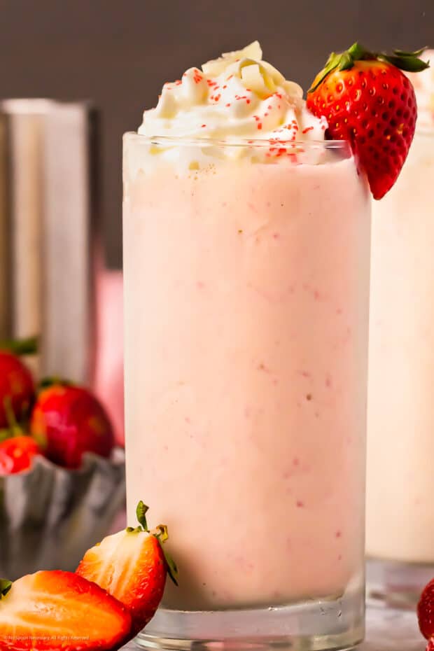 Straight on photo of a vodka milkshake with strawberries.