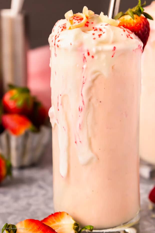 Straight on photo of a melting alcoholic milkshake with strawberries.