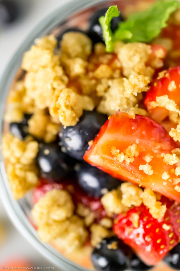 Overhead, up-close shot of a Parfait with the focus on a fresh strawberry and streusel crumbs.