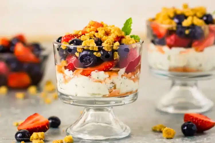 Straight on photo of a berry parfait made with greek yogurt, fresh berries, and streusel.