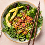 Overhead photo of a bowl of Poke Salad with mango poke dressing and wood chopsticks resting on the side of the bowl.