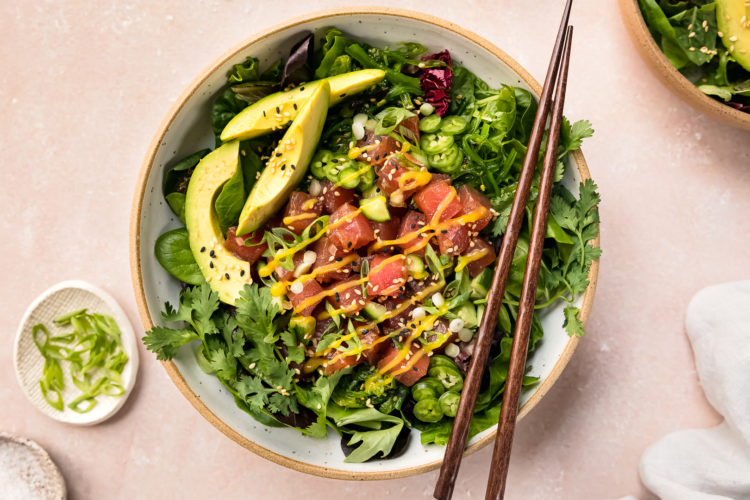 Overhead photo of a bowl of Poke Salad with mango poke dressing and wood chopsticks resting on the side of the bowl.