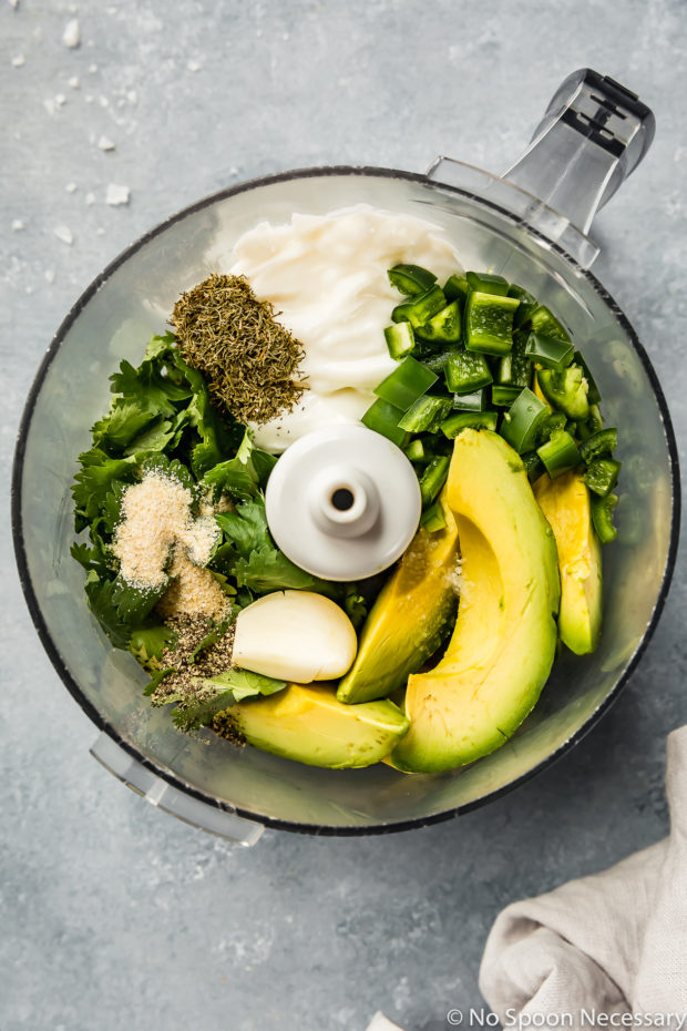 Overhead shot of a food processor bowl filled with all the ingredients needed to make avocado jalapeno ranch dressing. (Photo of step 2 of the recipe for summer corn BLAT salad)