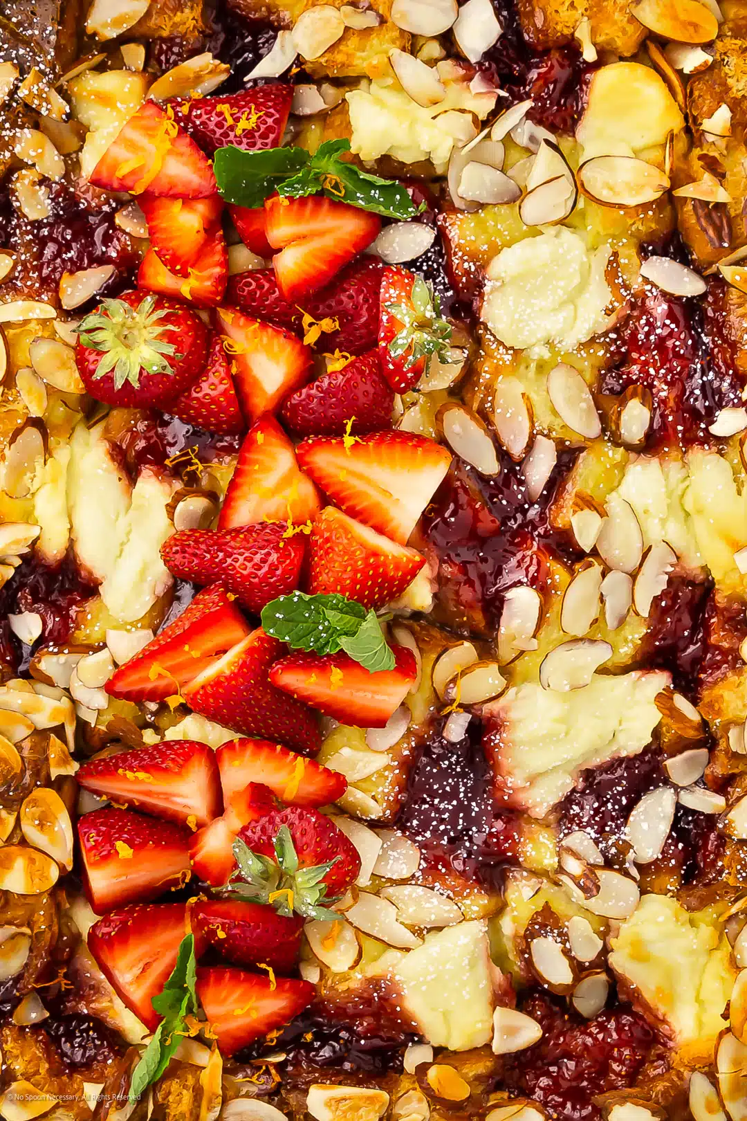 Close-up photo of a sweet breakfast bake with jam, berries, and ricotta cheese.