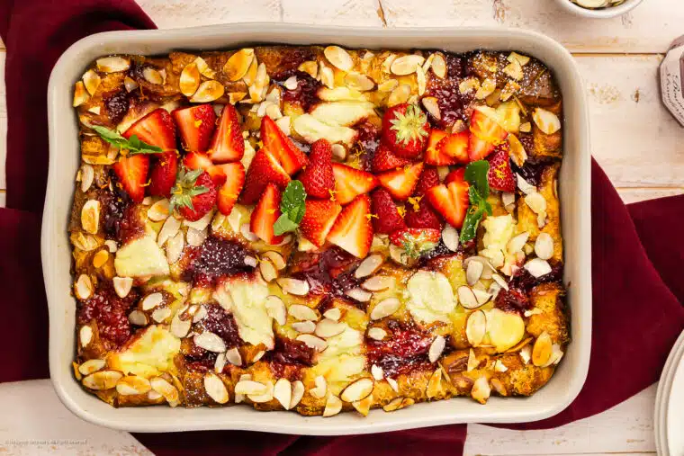Overhead photo of a sweet breakfast casserole with ricotta cheese, strawberry jam, and fresh strawberries.