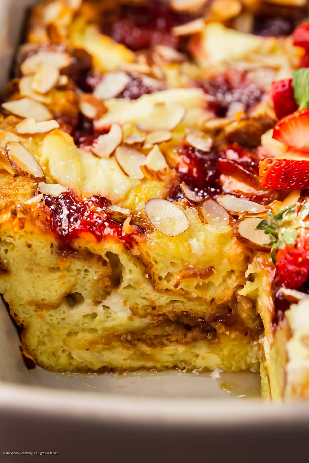 Close-up photo showcasing the layers of french toast, sweet jam, and ricotta cheese in a sweet brunch casserole.