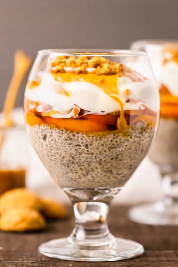 Straight on photo of a peach pudding with chia seeds and cream.