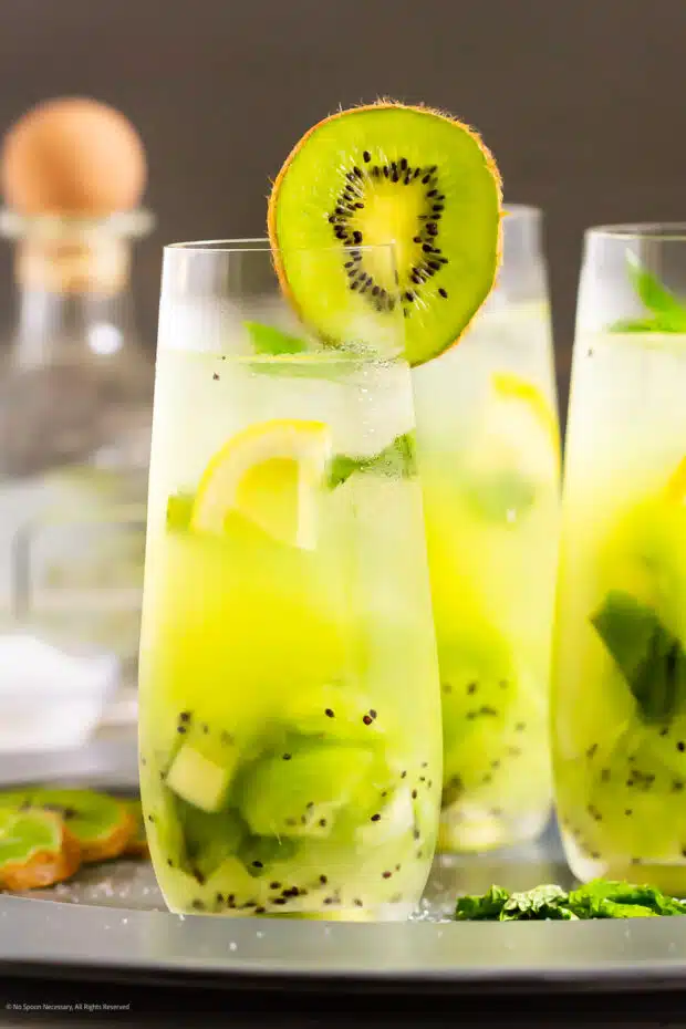 Straight on photo of a tequila cocktail with kiwi and lemon.