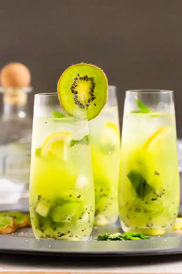Straight on photo of three kiwi drinks garnished with a slice of kiwifruit.