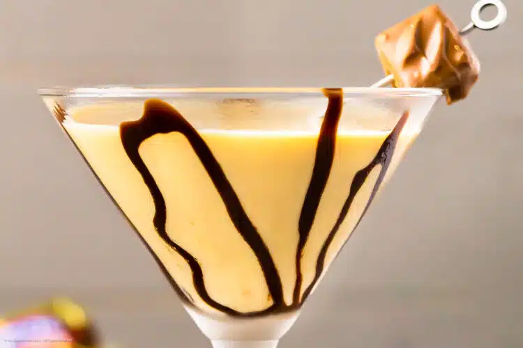 Straight on, up close shot of a Chocolate Martini garnished with chocolate syrup and a mini snickers chocolate bar.