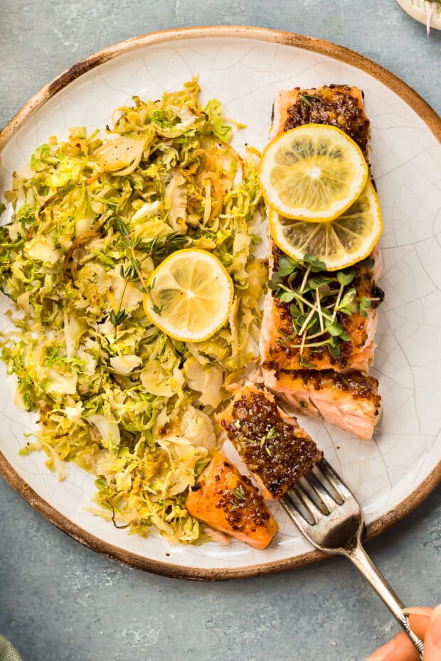 Overhead photo of a roasted filet of salmon with brussels sprouts on a white plate.