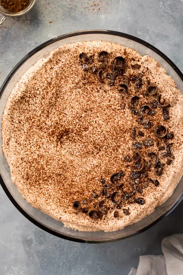Overhead photo of a trifle dessert garnished with cocoa powder and chocolate shavings.