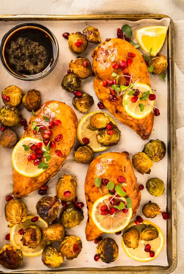 Close up photo of baked balsamic chicken and brussel sprouts on a sheet pan.