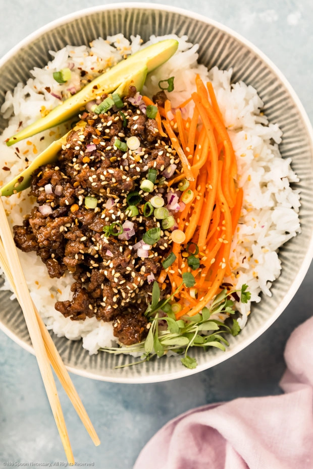 Overhead, close-up photo of Asian Beef Stir-Fry with sesame seeds, carrots and avocado on a bed of white rice. 