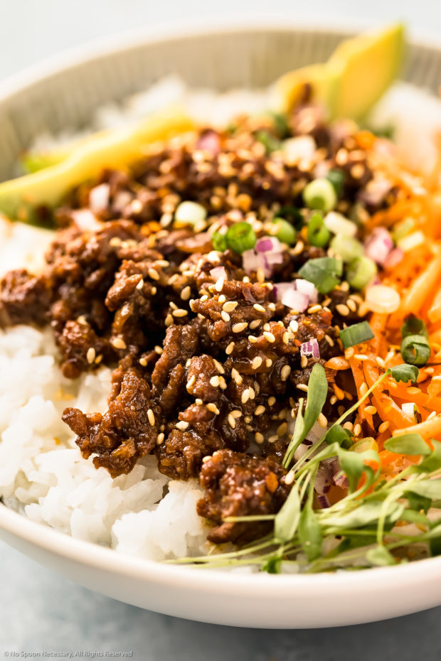 Straight on, close-up photo of ground beef stir fry garnished with sesame seeds and sliced scallions.
