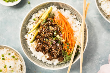 Overhead landscape photo of Chinese Beef Stir Fry on a bed of white rice with matchstick carrots and slices of avocado.