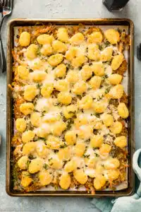 Overhead photo of a baking sheet with gnocchi baked in the oven with cheese and onions.
