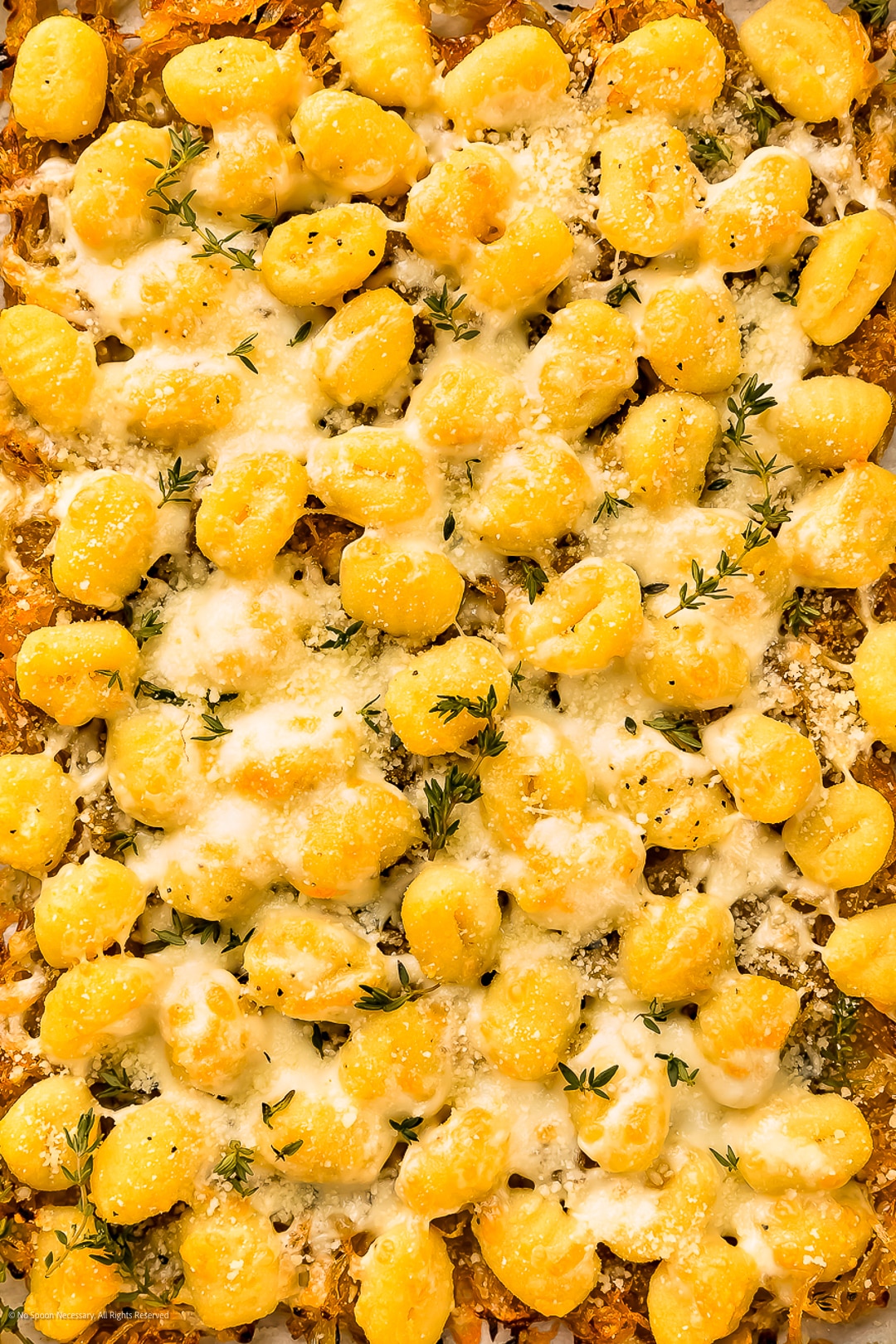 Close-up photo of baked gnocchi with cheese and herbs.