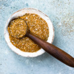 Overhead photo of Homemade Sazon Seasoning Mix in a ramekin with a small wooden spoon full of seasoning resting on the ramekin.