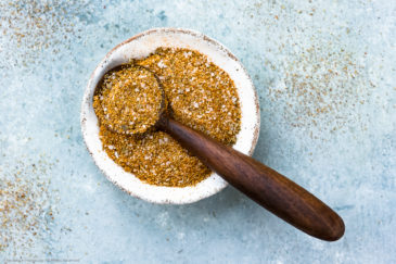 Overhead photo of Homemade Sazon Seasoning Mix in a ramekin with a small wooden spoon full of seasoning resting on the ramekin.