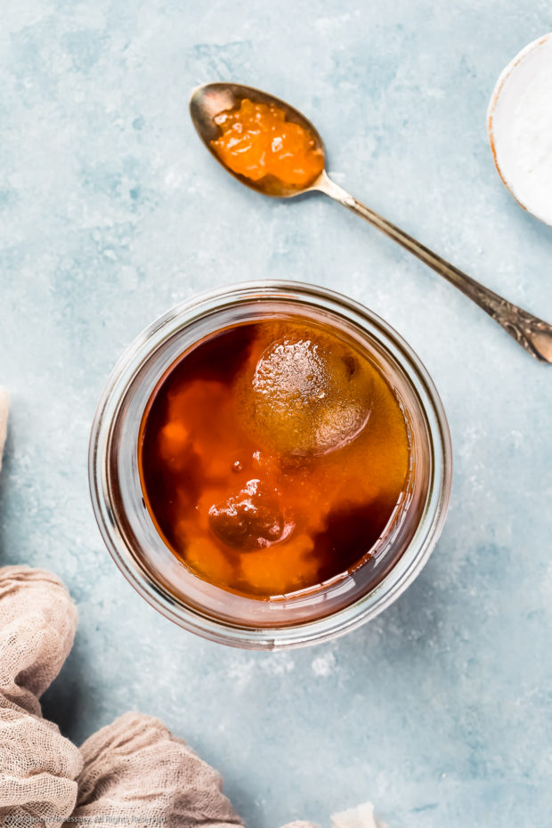 overhead of apricot sauce in a jar and on a spoon