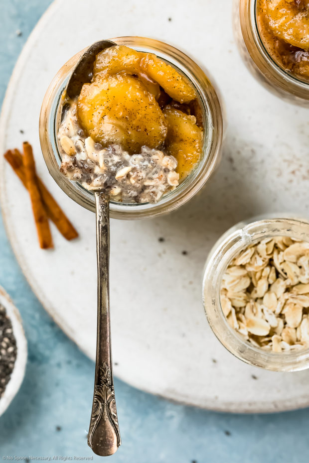 Overhead photo of a jar of Overnight Oats with a spoon inserted into the jar, lifting up the banana topping.