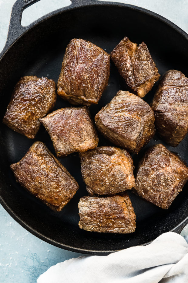 Overhead photo of seared and browned beef short ribs in a cast iron skillet - photo of step 2 of the recipe.