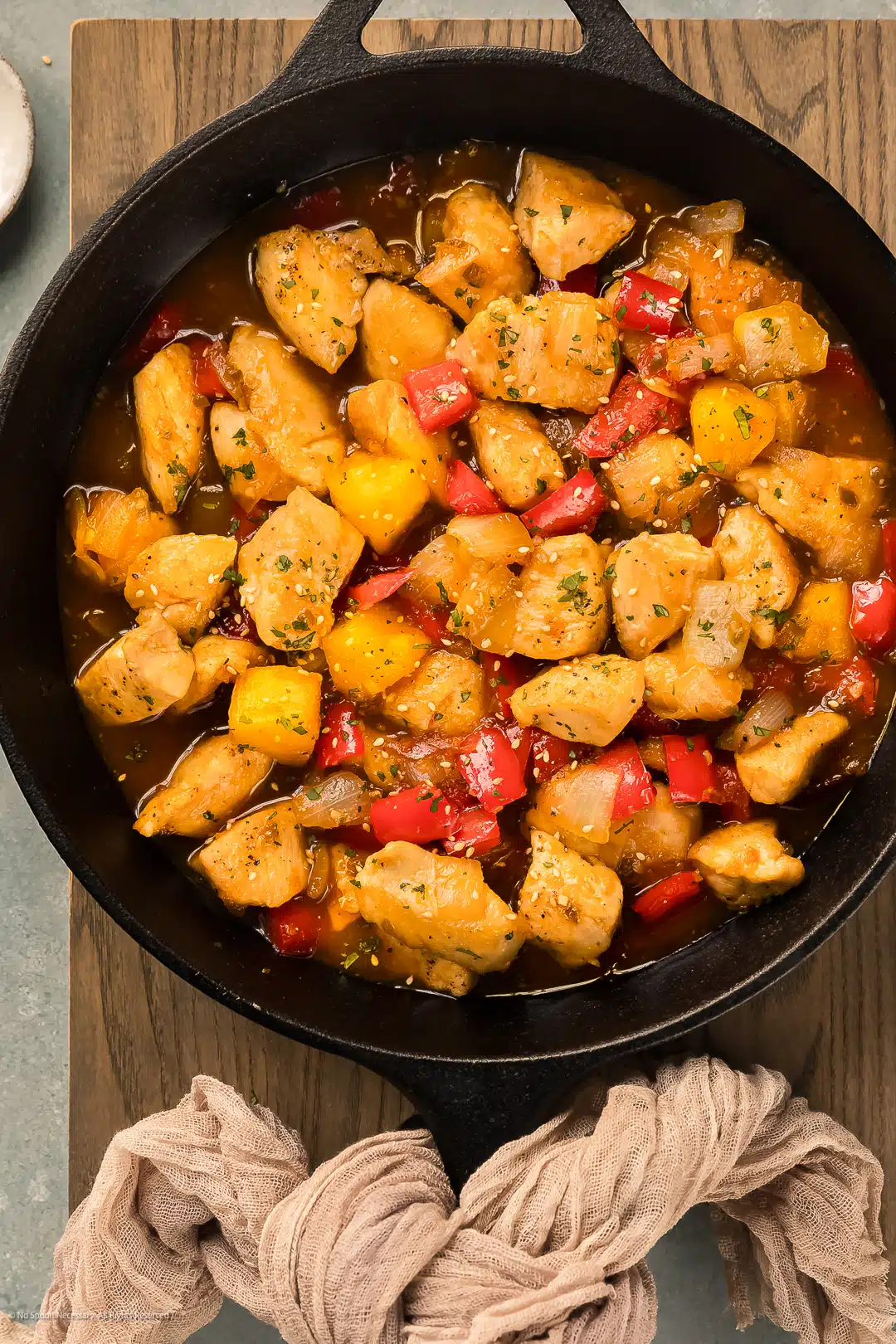 Overhead photo of chicken and apricots stir fry in a large cast iron skillet.