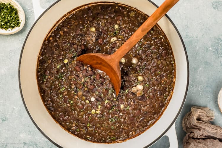 Overhead photo of cooked cuban black beans in a large white pot.