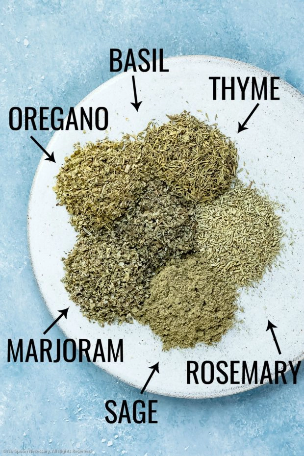 Overhead photo of the main ingredients in Italian seasoning neatly arranged on a plate with the name of each ingredient written out next to it - photo of step 1 of the recipe.