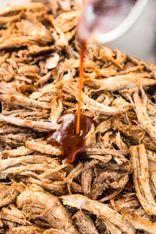 Angled photo of Carolina-style BBQ sauce being poured over pulled pork.