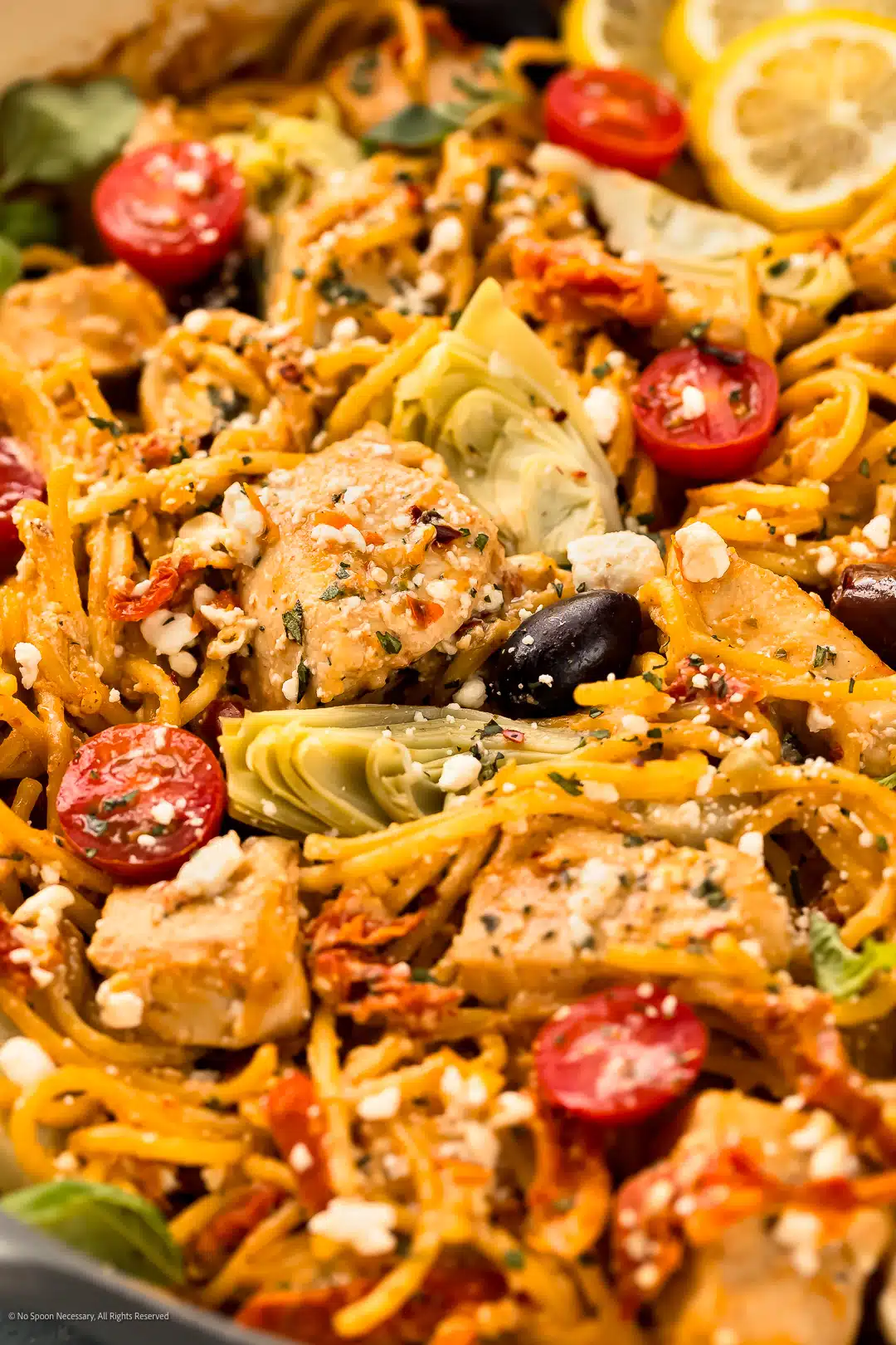 Angled photo showcasing the chunky texture of greek chicken with pasta.