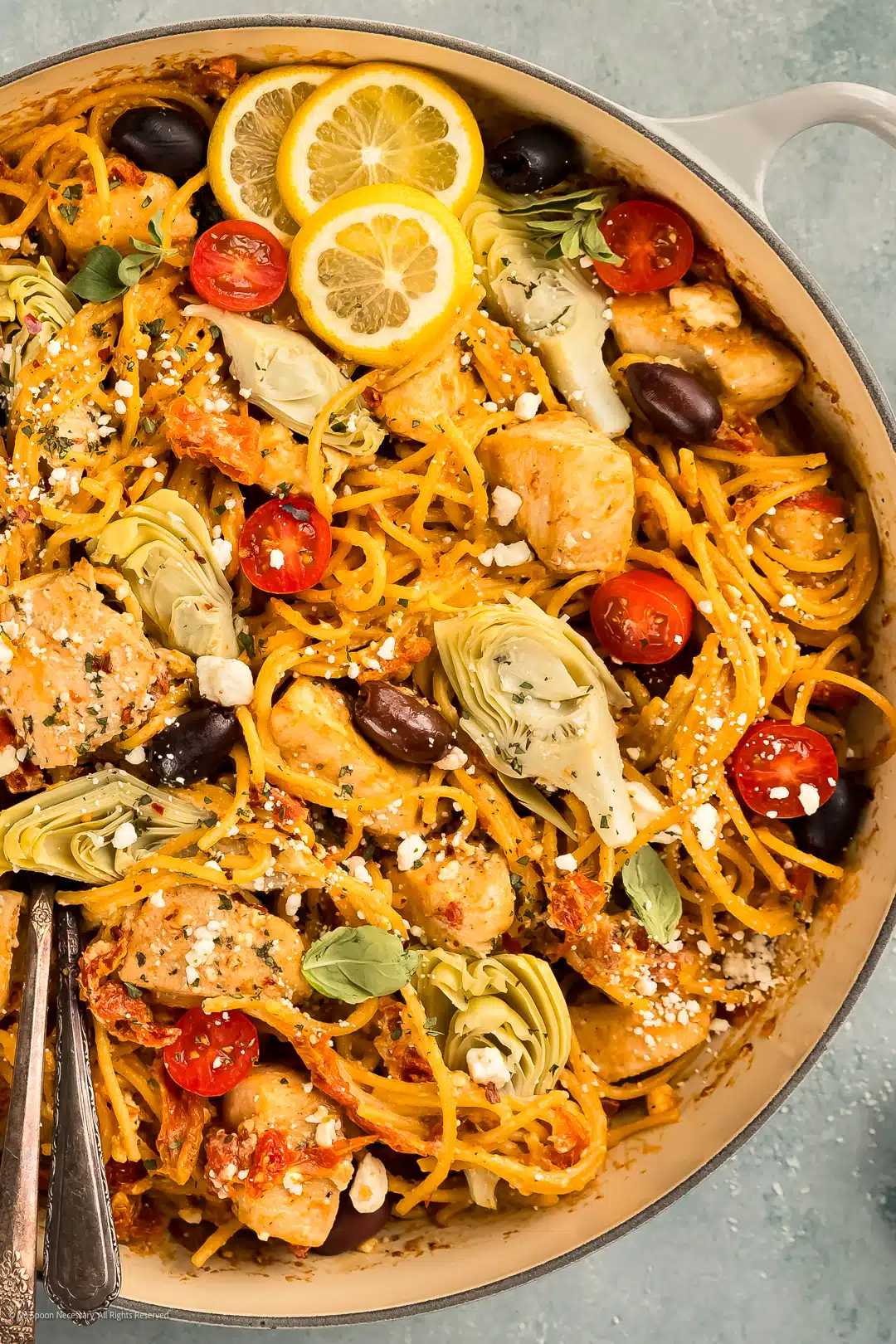 Overhead photo of greek chicken and pasta with veggies in a large skillet.