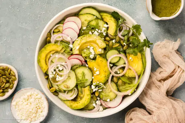 Overhead photo of cucumber avocado salad in a white bowl.