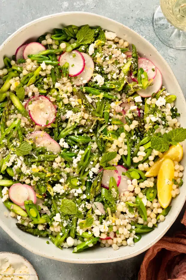 Photo of lemony pearl couscous salad with asparagus in a serving bowl.