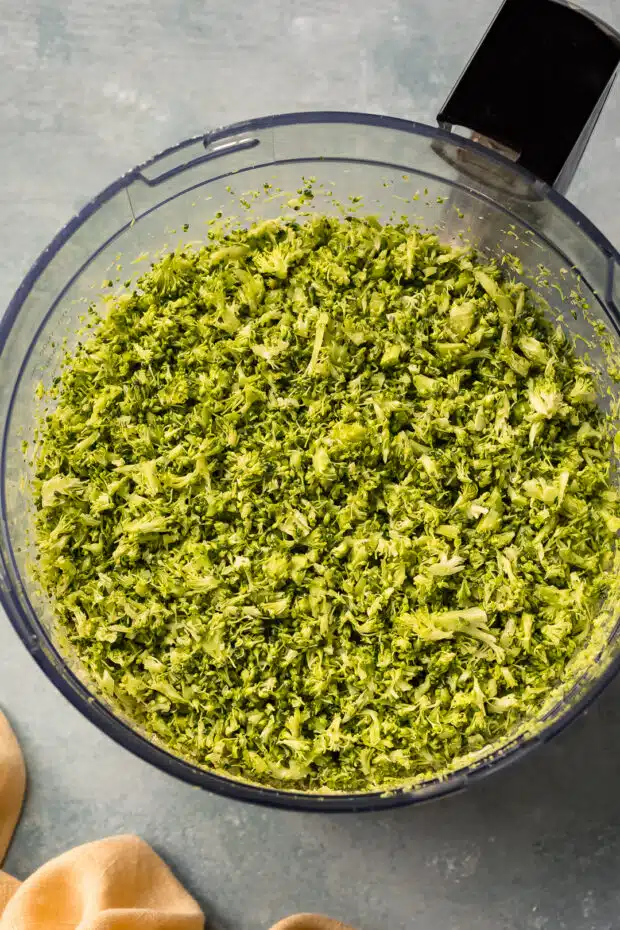 Overhead photo of broccoli rice in the bowl of a food processor. 