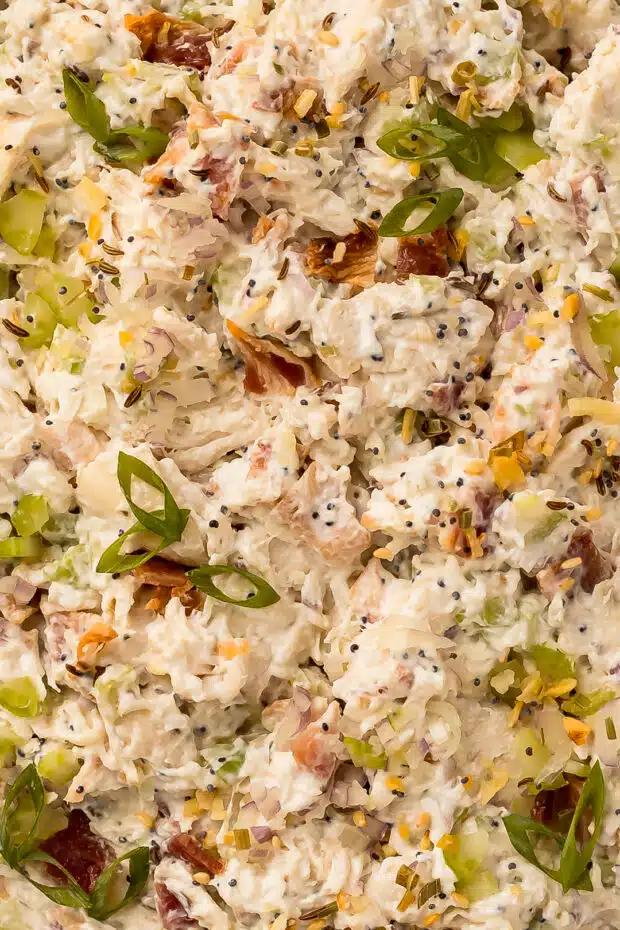 Close-up photo of a creamy cream cheese based salad with chicken, bacon, celery, onions, and fresh herbs.