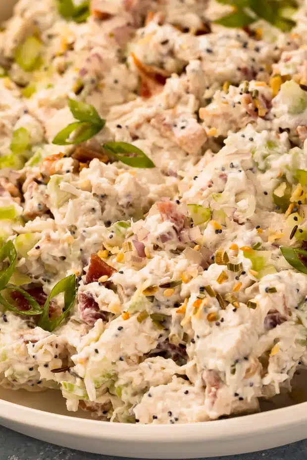 Close-up angled photo of creamy chicken salad with cream cheese, bacon, veggies, and fresh herbs
